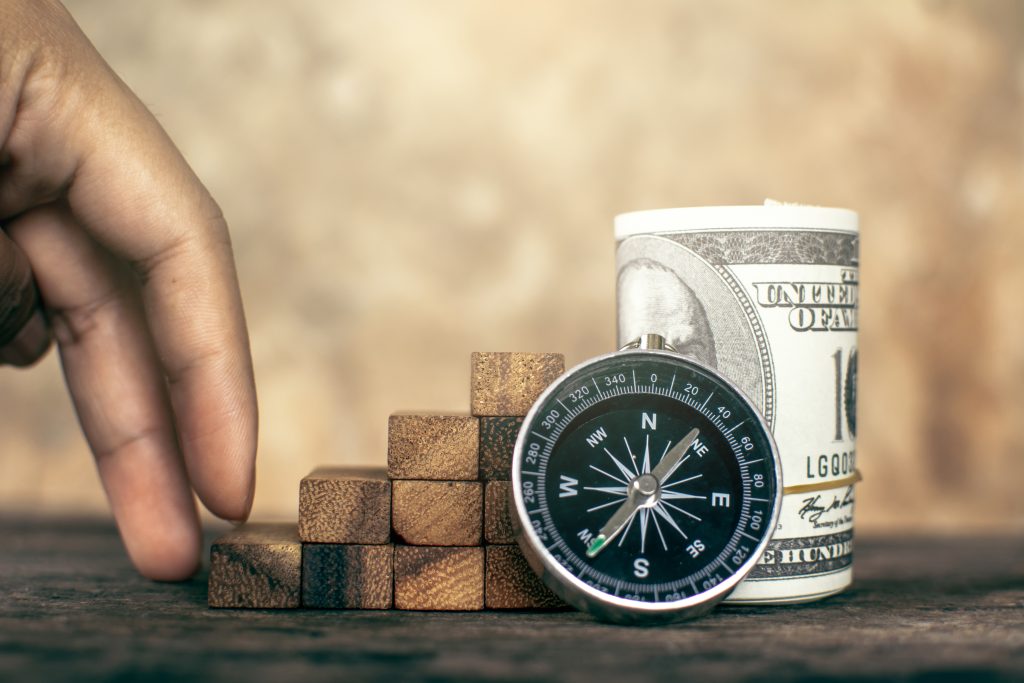 Hand walking on step wood with compass and money, Direction of the economy.